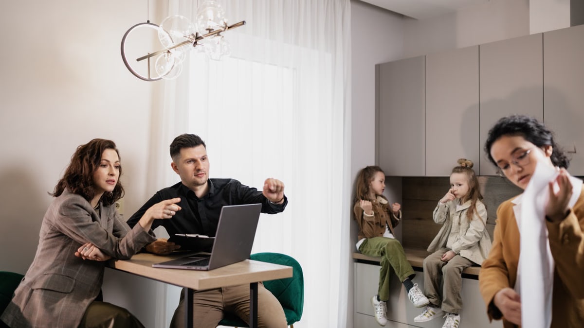 Family discussing real estate purchase inside home with agent and children present.