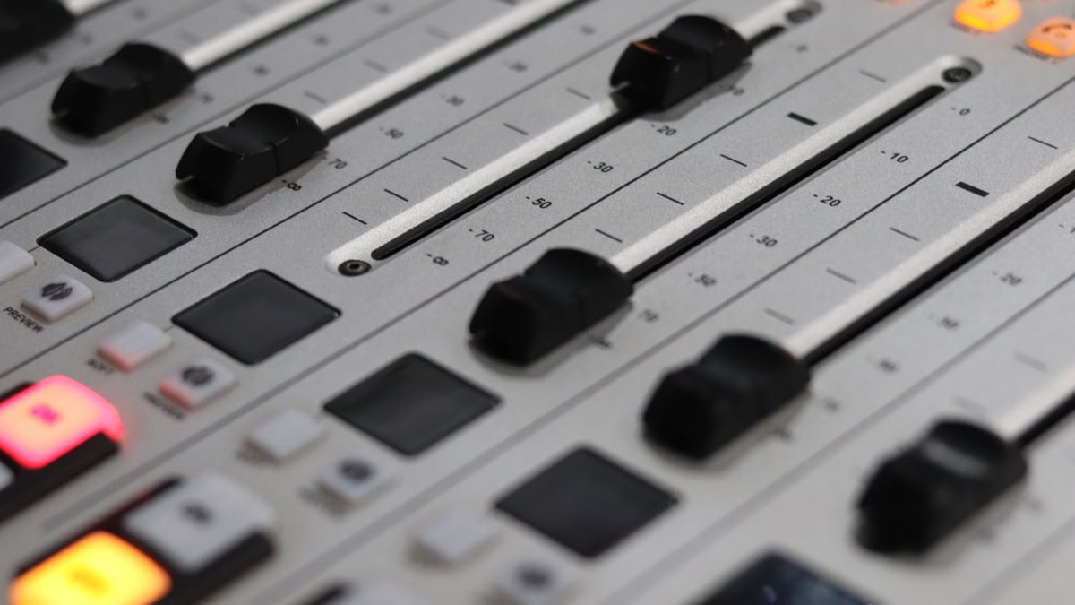 Close-up view of a professional audio mixer with sliders and control knobs, ideal for sound production.